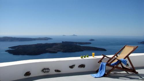 a chair sitting on a ledge with a view of the ocean at Irida - Santorini in Imerovigli