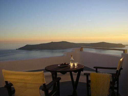 a table with a bottle of wine and two chairs at Irida - Santorini in Imerovigli