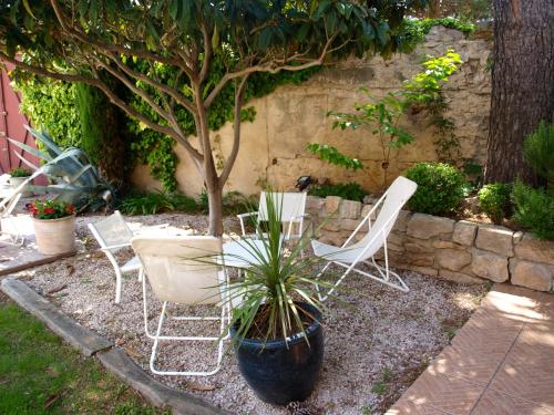 a group of chairs and a tree in a garden at Le relais d'Angélique in Lunel