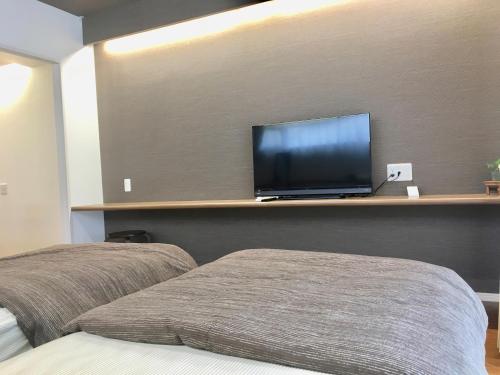 a bedroom with two beds and a flat screen tv at A-Style Futenma in Ginowan