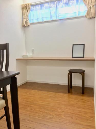 a desk with a laptop and a stool under a window at A-Style Futenma in Ginowan