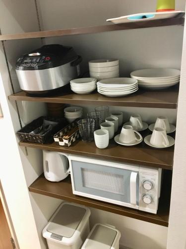 a kitchen with a microwave and plates and dishes at A-Style Futenma in Ginowan
