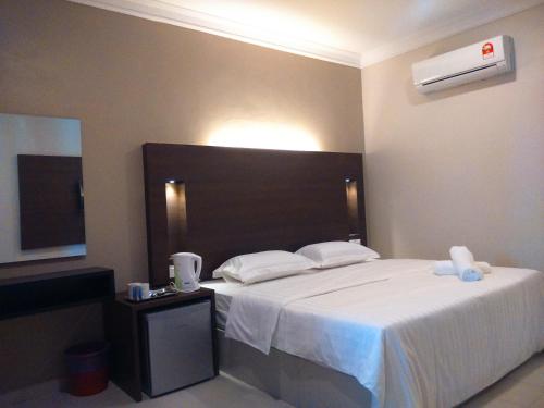1 dormitorio con 1 cama blanca grande y TV en Ziella De Villa, en Pantai Cenang