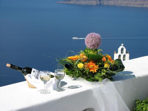 a table with a bouquet of flowers and wine glasses at Irida - Santorini in Imerovigli