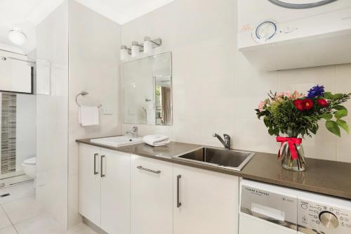 una cocina blanca con fregadero y un jarrón de flores en Headland Tropicana Resort, en Alexandra Headland