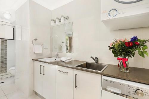 a white kitchen with a sink and a vase of flowers at Headland Tropicana Resort in Alexandra Headland