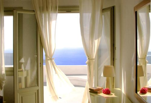 a bedroom with a view of a bed and a window at Irida - Santorini in Imerovigli