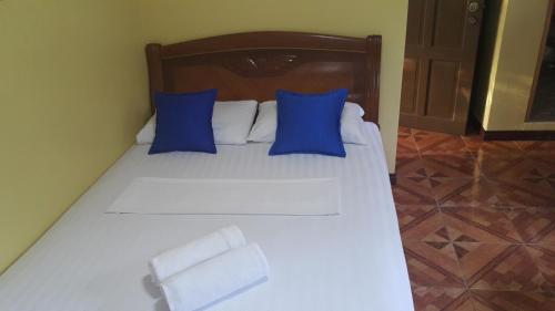 a white bed with blue pillows in a room at Carribean Transient House in Lucap