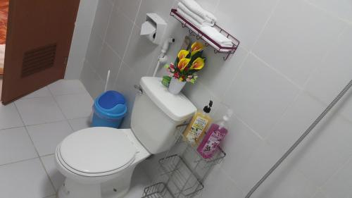 a bathroom with a white toilet and flowers on the tank at Carribean Transient House in Lucap