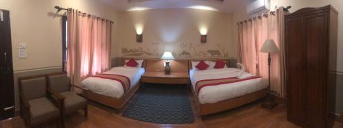 a hotel room with two beds and a desk in it at Jungle Safari Resort in Sauraha