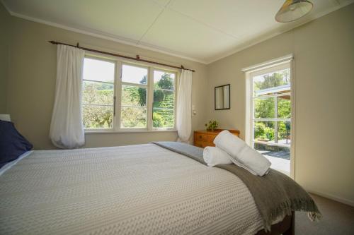 Mahaanui Cottage Farmstay في Tiniroto: غرفة نوم بسرير كبير مع نافذتين