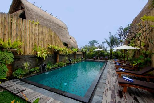 una piscina en un complejo con sillas y sombrillas en De Klumpu Bali Eco Tradi Stay, en Bangli