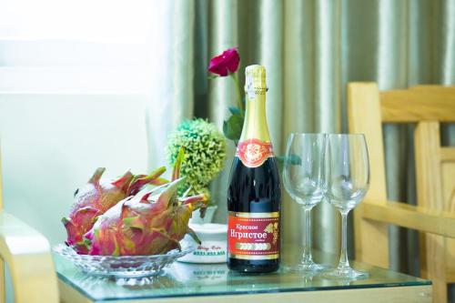 a bottle of wine next to a bowl of flowers and a wine glass at Dang Quang Guesthouse in Ha Long