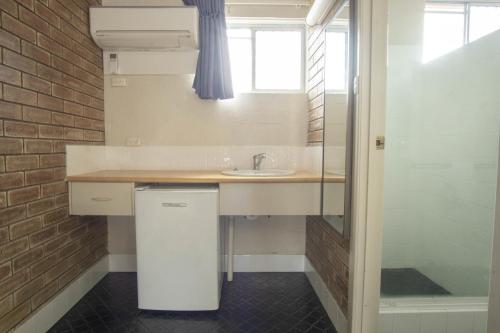 a small bathroom with a sink and a shower at Acacia Motor Inn in Bundaberg