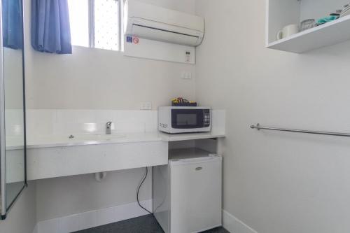a small kitchen with a microwave and a sink at Acacia Motor Inn in Bundaberg