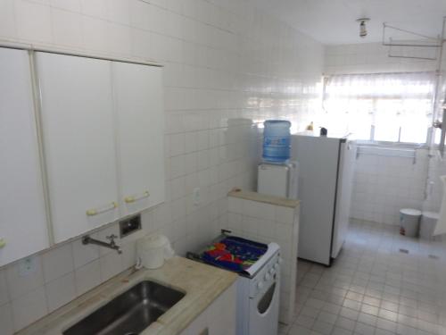 eine weiße Küche mit einer Spüle und einem Kühlschrank in der Unterkunft Apartamento praia do forte in Cabo Frio