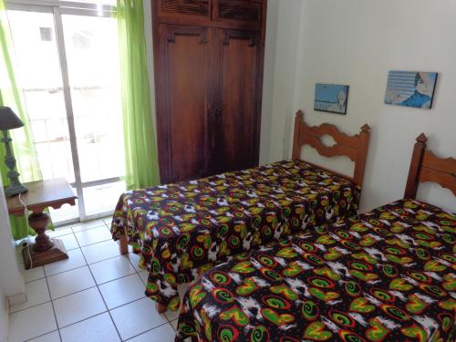 ein Schlafzimmer mit einem Bett mit einer bunten Decke darauf in der Unterkunft Apartamento praia do forte in Cabo Frio
