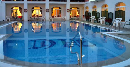 uma grande piscina num hotel com mesas e cadeiras em Hotel Caribe em Rota