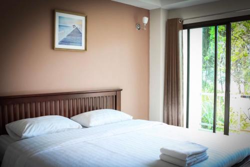 una camera da letto con un letto e due asciugamani di Yellow House Rayong a Ban Phe