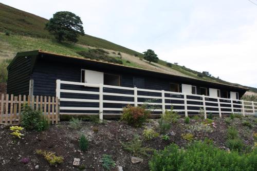 a black house with a white fence in front of it at The White Horse Inn Bunkhouse in Threlkeld