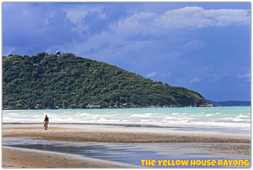 a person walking on a beach near the ocean at Yellow House Rayong in Ban Phe