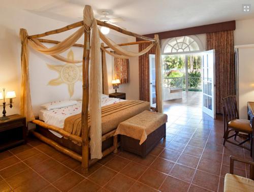 a bedroom with a canopy bed and a patio at Hotel Villa Serena in Las Galeras