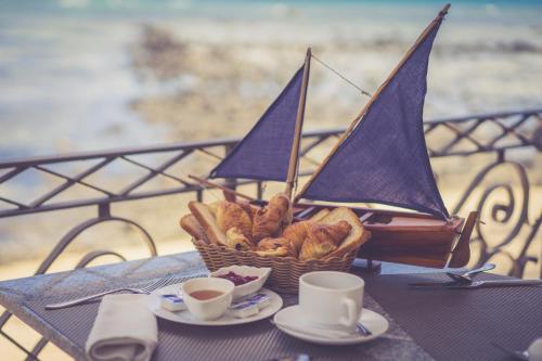 a table with a basket of bread and cups of coffee at Voile Bleue Boutique Hotel in Trou aux Biches