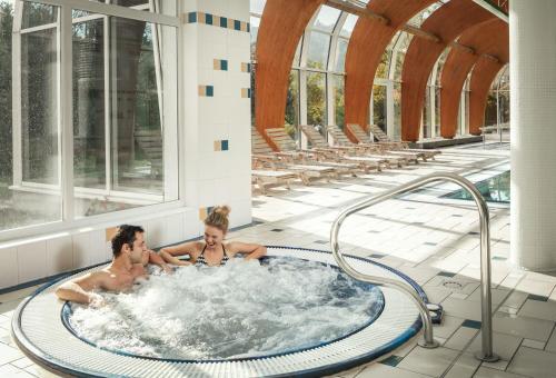 a man and a woman swimming in a pool at Spa Resort Sanssouci in Karlovy Vary