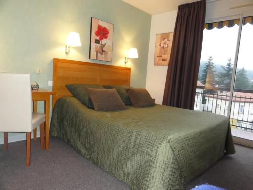 a bedroom with a bed and a desk and a window at Hotel Princess in Vernet-les-Bains