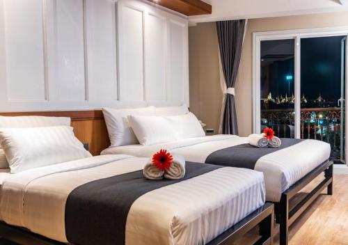 two beds in a hotel room with red flowers on them at Dang Derm In The Park Khaosan in Bangkok