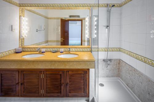 een badkamer met 2 wastafels, een spiegel en een bad bij Quinta Golf & Beach House in Quinta do Lago