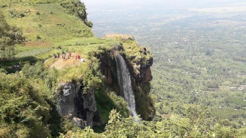 a group of people standing on a cliff next to a waterfall at SALEM Eco-Lodge & Guesthouse in Mbale