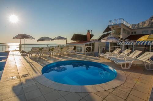 a swimming pool on a patio with chairs and umbrellas at Aparthotel Pecic in Gradac