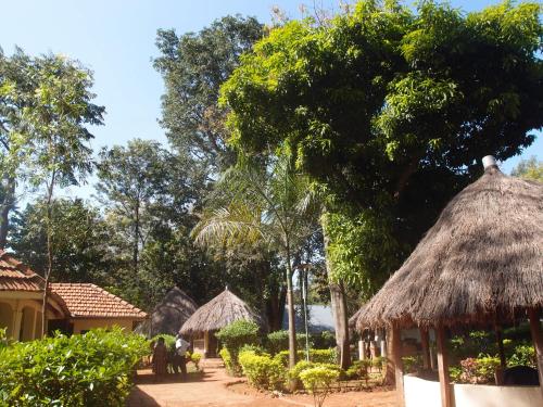a group of huts and trees with people sitting outside at SALEM Eco-Lodge & Guesthouse in Mbale