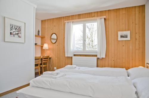 1 dormitorio con 3 camas blancas y ventana en Apartment Nussbaum - GRIWA RENT AG, en Grindelwald