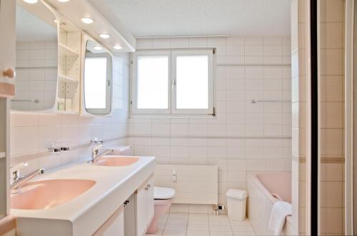 a bathroom with two sinks and a tub and a toilet at Apartment Neuenhaus - GRIWA RENT AG in Grindelwald