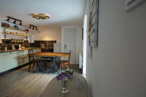 a kitchen with a table with a vase of flowers on it at Vendégház az Evezőhöz in Szigetszentmiklós