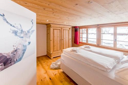 a bedroom with a white bed in a room with wooden floors at Chic Alpine Apartment for 5 - Perfect for skiers in Grindelwald