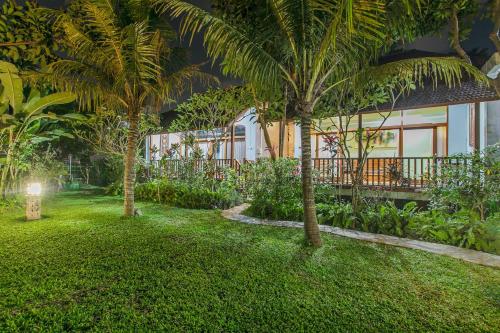 a garden in front of a house with palm trees at Villa D'Carik Bali in Denpasar