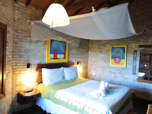 a bedroom with a bed and a lamp and paintings at Pousada Cantinho das Estrelas in Monte Verde
