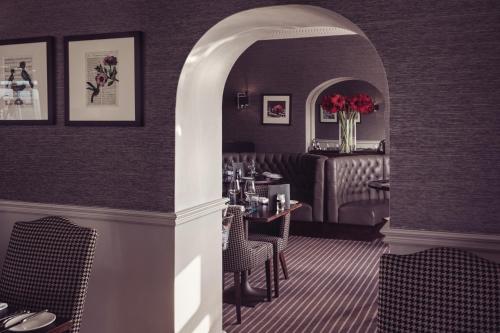 a dining room with a table and chairs and a room with at Windermere Hillthwaite Hotel in Windermere