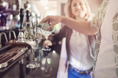 a woman pouring wine into a glass at a bar at Windermere Hillthwaite Hotel in Windermere