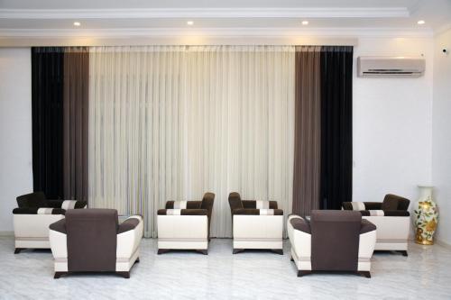 a waiting room with white chairs and curtains at Consul Hotel in Baku