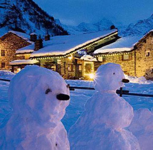 two snowmen standing next to each other in front of a building at Hotel Restaurant La Barme in Cogne
