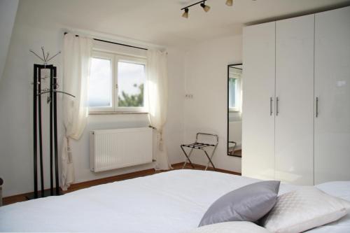 a white bedroom with a large bed and a window at Apartment Sonnenterrasse in Baden-Baden