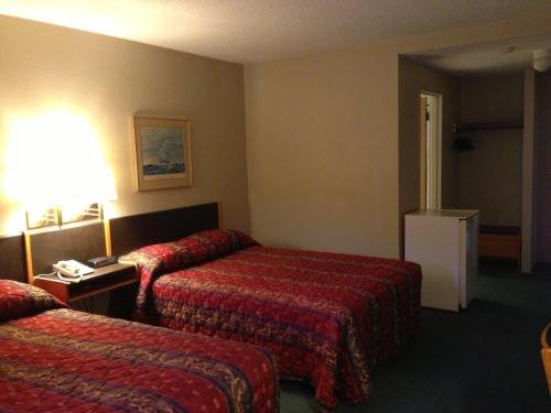 a hotel room with two beds and a desk at Moby Dick Inn in Prince Rupert