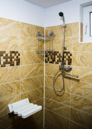 a bathroom with a shower with a tile wall at Pensiunea SilvAnka in Vîlcele