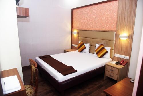 Una habitación de hotel con una cama, una mesa y un escritorio. en Hotel Indiana Inn, en Navi Mumbai