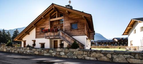 a wooden house with a balcony and a stone wall at Agriturismo La Stalla in Bormio