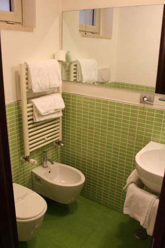 a green tiled bathroom with a sink and a toilet at Albergo Miramonti in Potenza